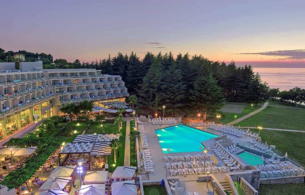 Hotel Mediteran Plava Laguna resort with illuminated pool and outdoor dining at sunset