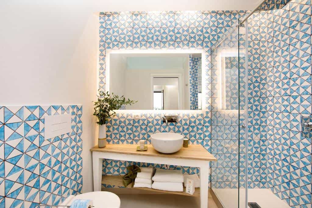 Bathroom vanity with vessel sink, illuminated mirror, and blue geometric tiles, Sorrento style.