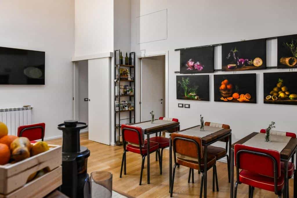 Dining area with fruit crate, juicer, and vegetable still life art in Ballarooms B&B Palermo Centro.