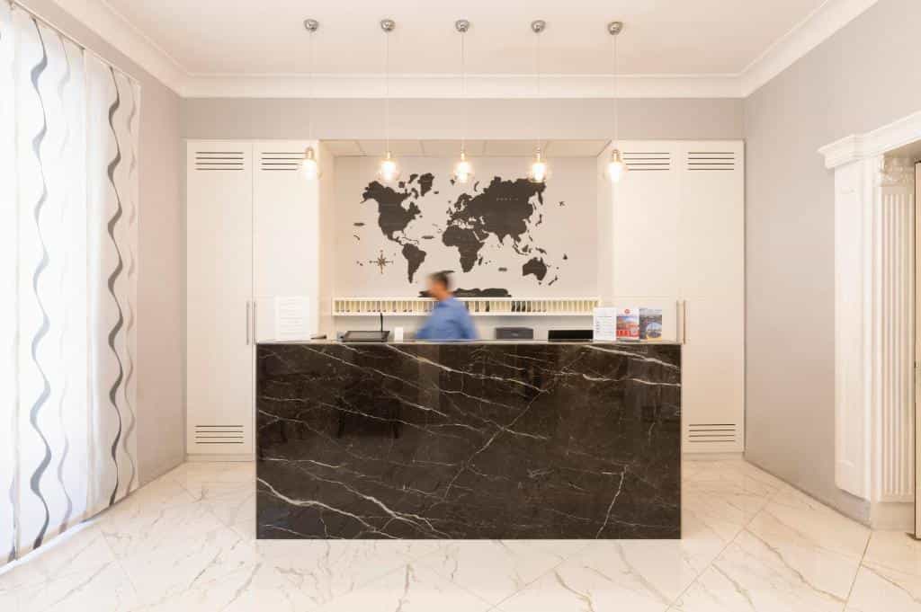 Hotel reception desk with black marble counter and world map backdrop