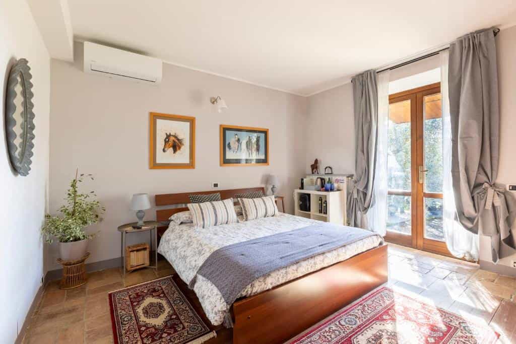 Bedroom with wooden bed, horse art, and patio doors in B&B La Casetta di Ben.