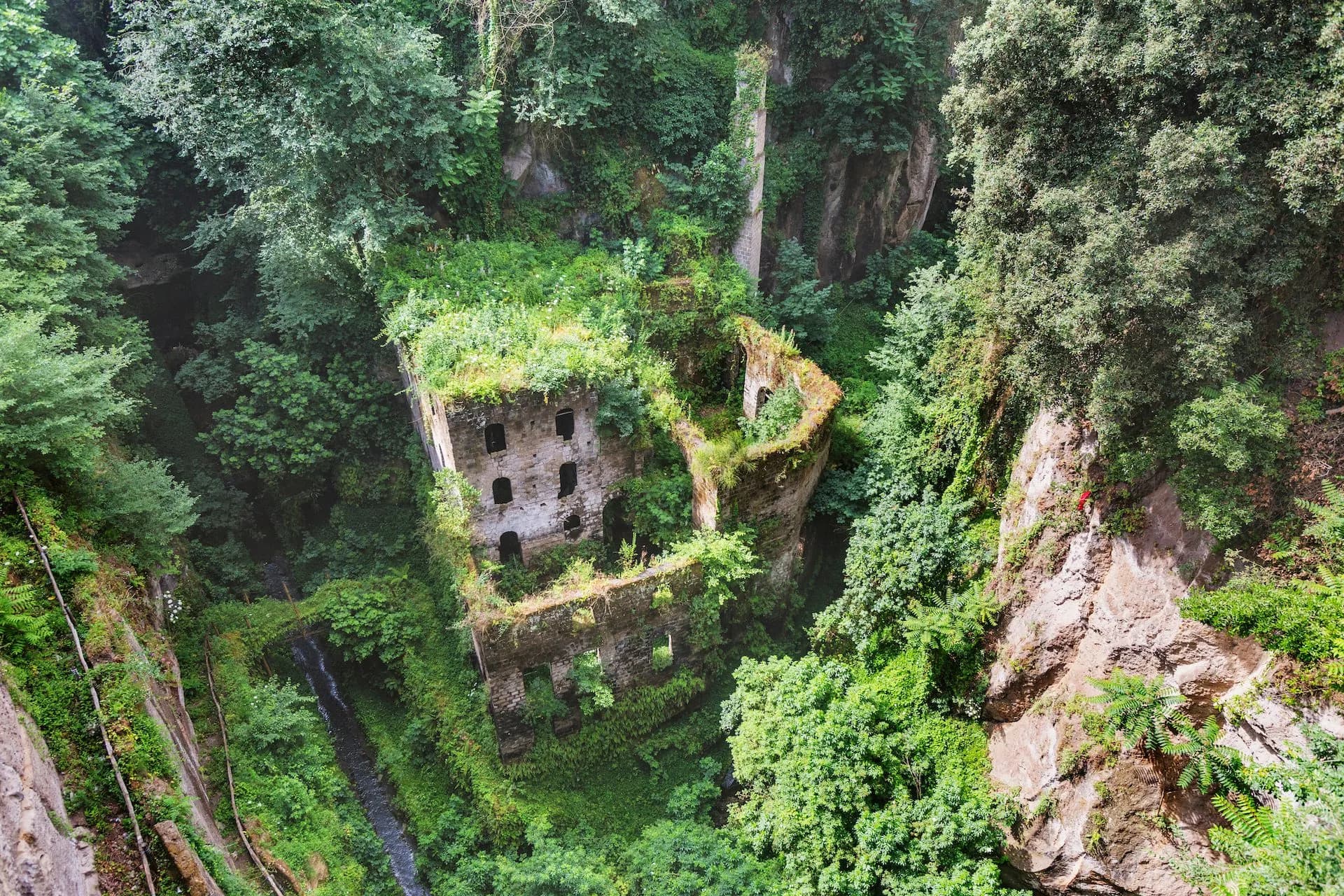 Ruins of Valle dei Mulini overgrown with lush greenery in a deep gorge near Sorrento.