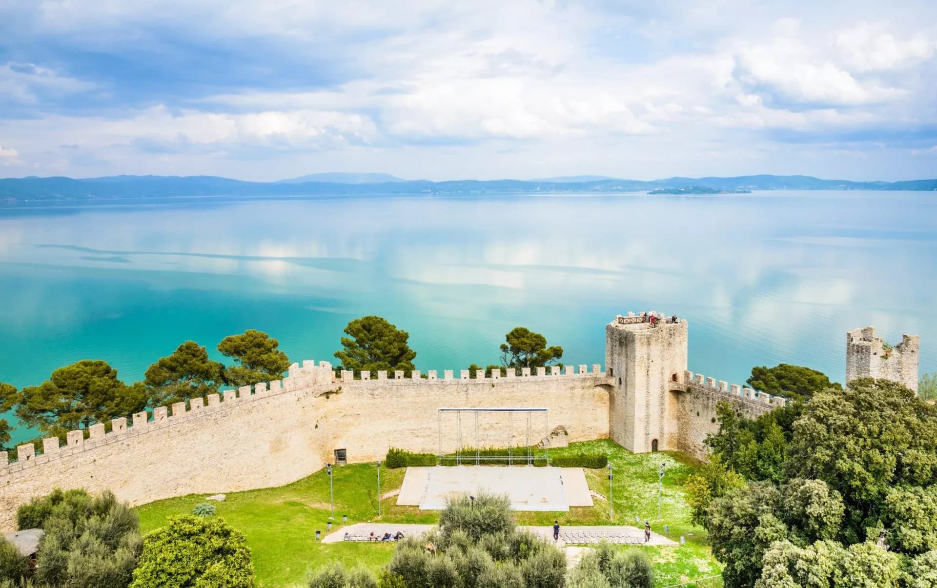 Panoramic view of stone fortress walls overlooking the turquoise waters of Lake Trasimeno.