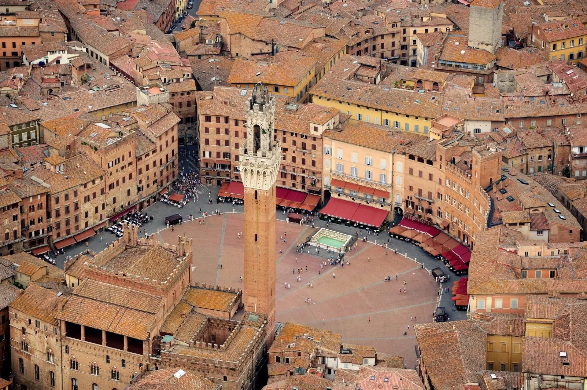Aerial view of Siena's Piazza del Campo with Torre del Mangia and terracotta rooftops.