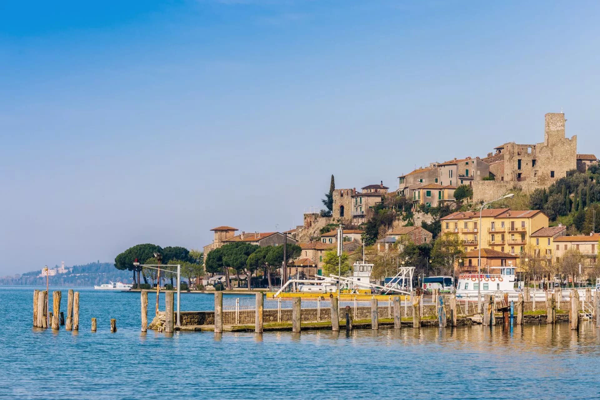 Lakeside town with historic buildings climbing a hill above a wooden pier and blue water