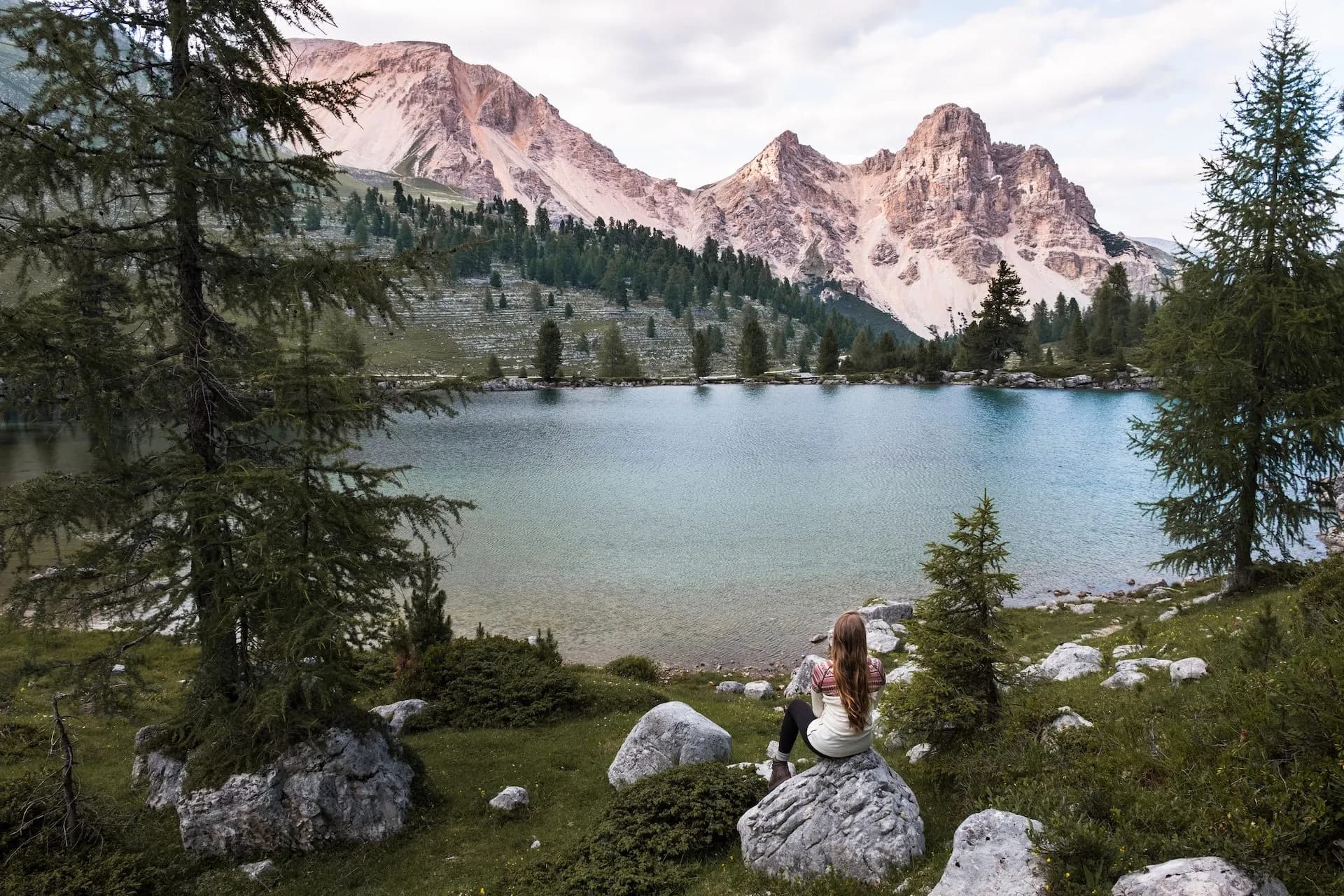 Woman sitting on rock overlooking Le Vert Lake with mountains and pine trees