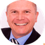 Close-up portrait of smiling man in suit and striped tie against white background