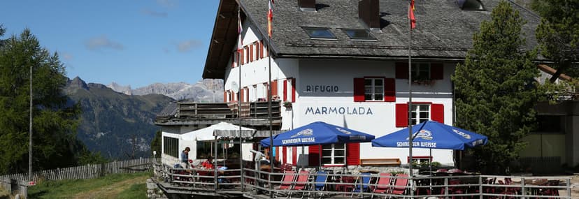 Rifugio Castiglioni Marmolada mountain hut with outdoor seating and distant alpine peaks.