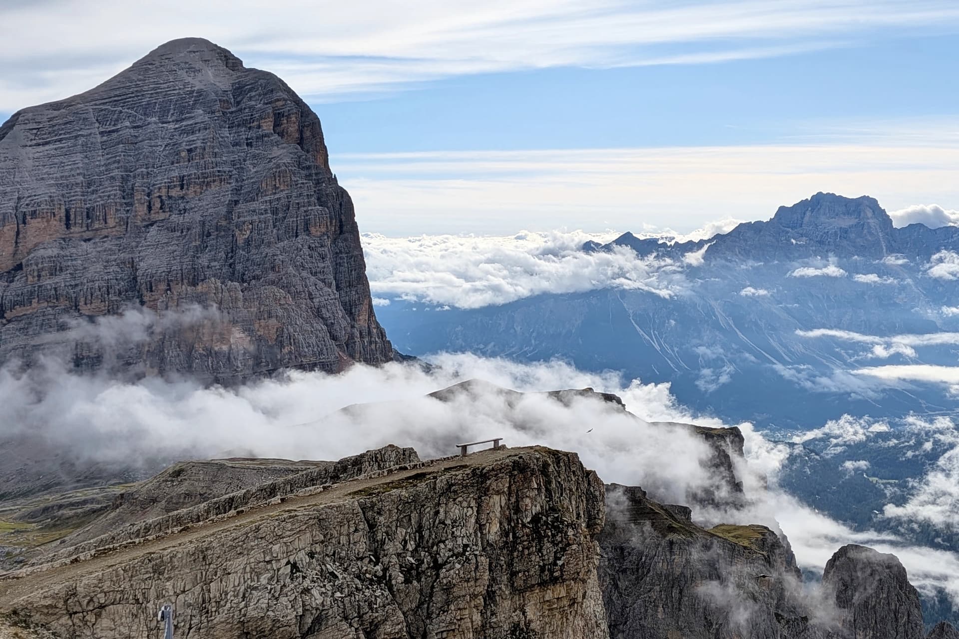 Rocky mountain tower rising above sea of clouds with distant peaks