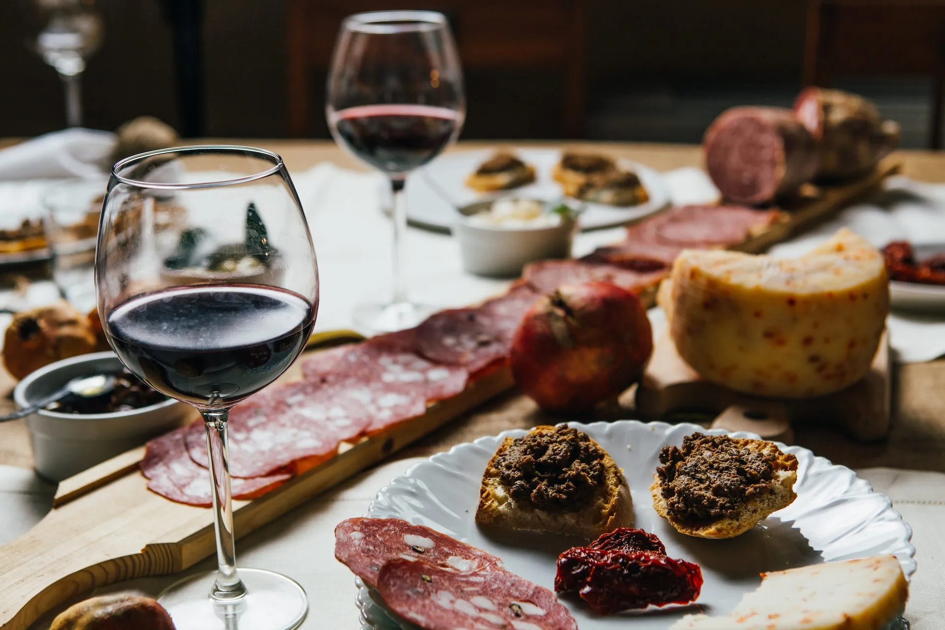 Red wine and charcuterie board with cheese, bruschetta, and salami in Chianti setting.