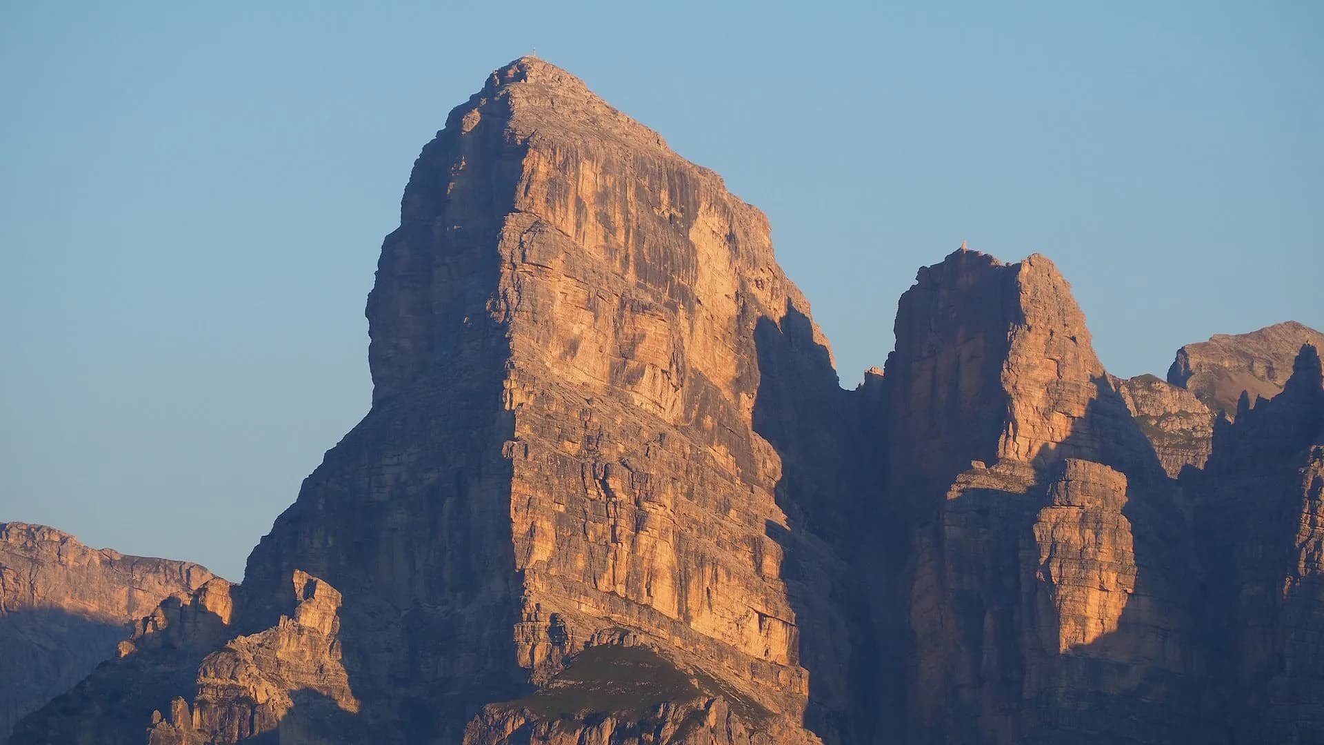 Rugged, sunlit mountain peaks against a clear blue sky, likely in the Gardenaccia Mountains.