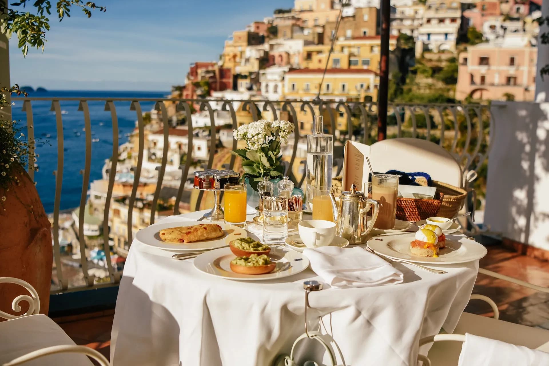 Breakfast on a balcony overlooking the colorful terraced buildings and Mediterranean Sea in Italy.