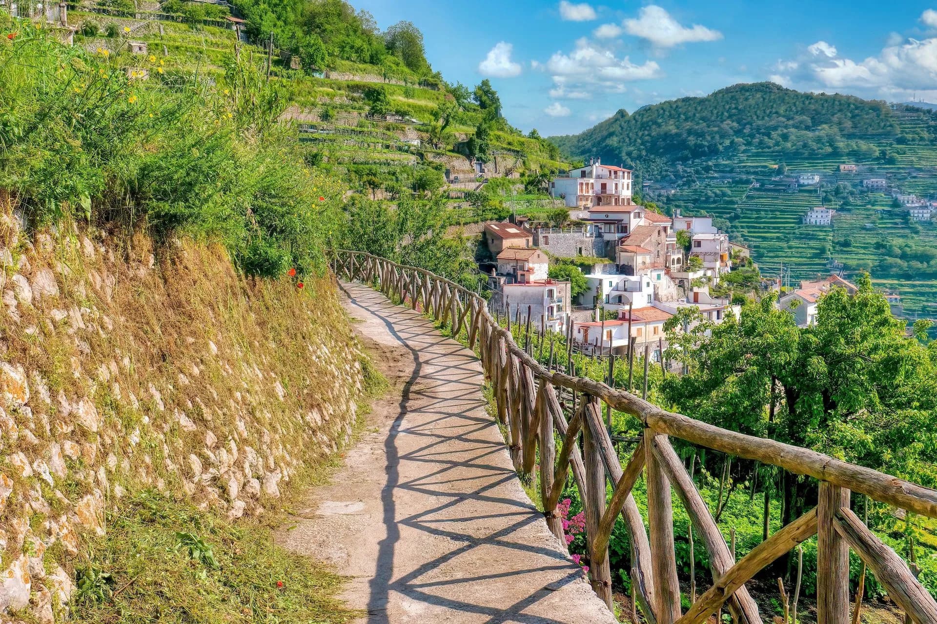 Scenic footpath with wooden railing near Scala overlooking terraced hills and white houses near Amalfi.