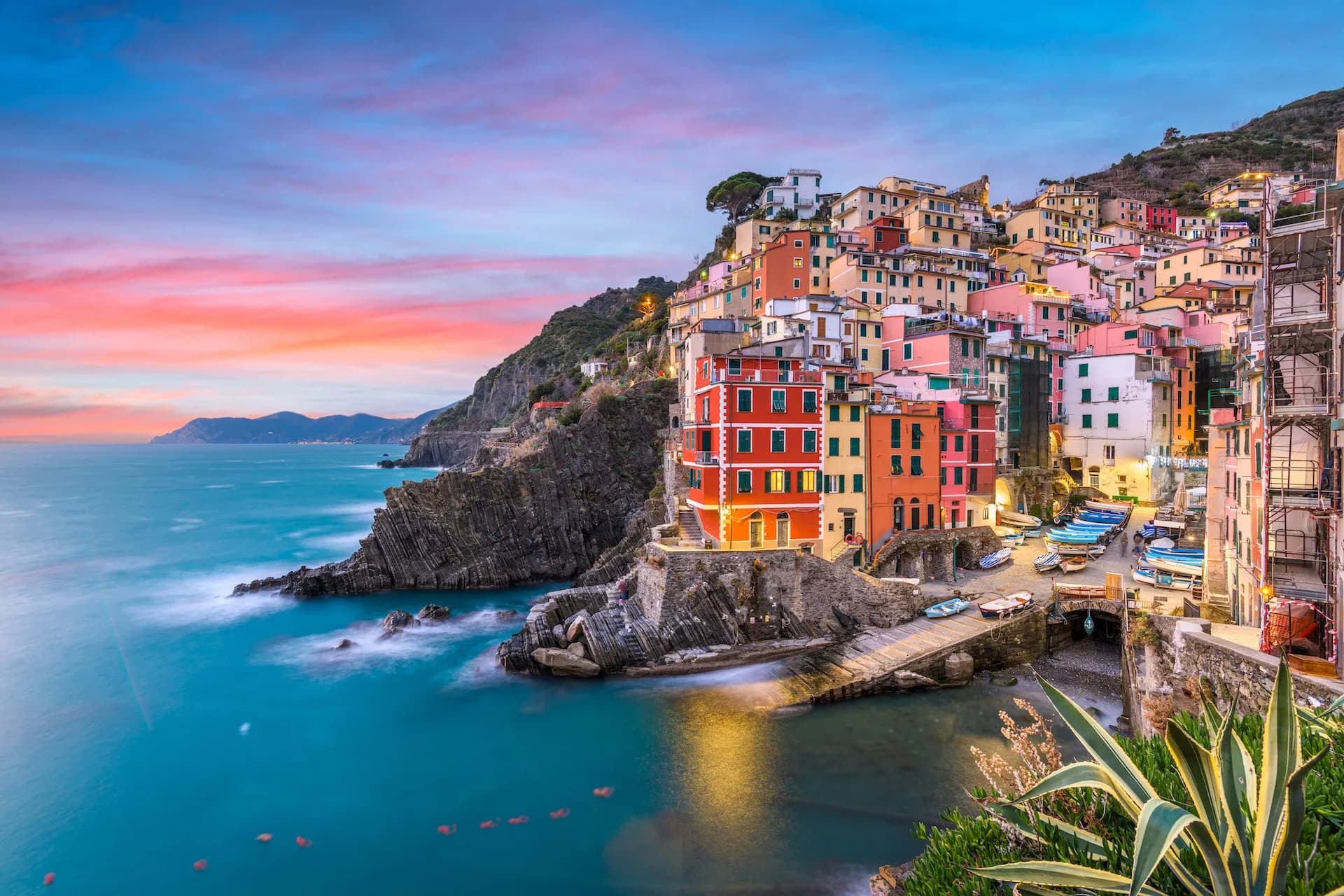 Colorful cliffside houses of Riomaggiore above turquoise sea at sunset