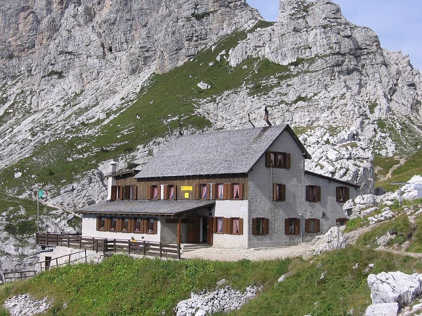 Rifugio Adolfo Sonino al Coldai mountain hut nestled against a steep, rocky alpine slope.
