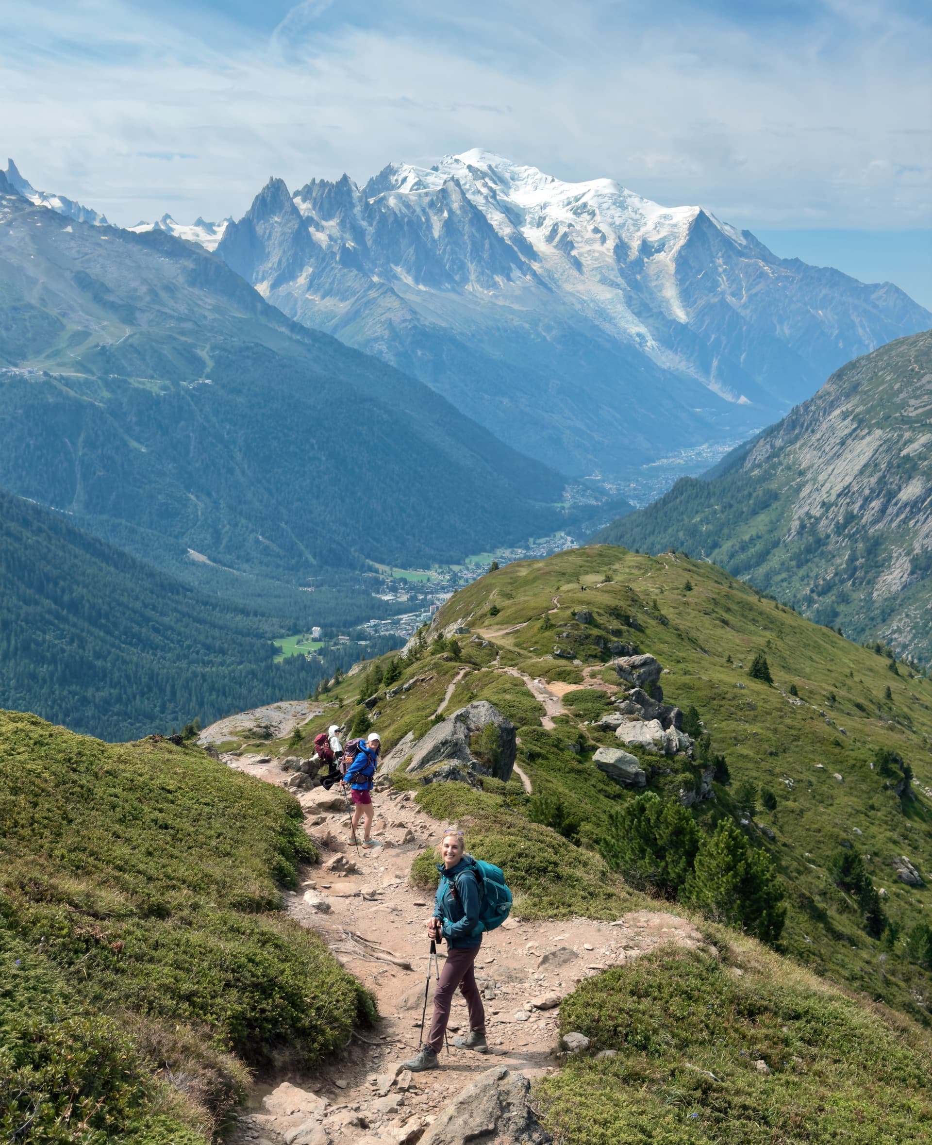 Hikers on alpine trail with snow-capped mountain peaks in the background