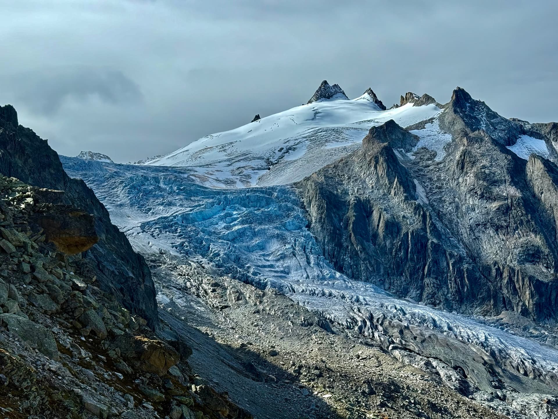 Glacier tumbling down a rocky alpine valley with snow-capped peaks